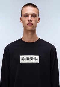 Black long-sleeve T-shirt in cotton with a rectangular white graphic featuring "NAPAPIJRI" and "geographic" in bold typography.