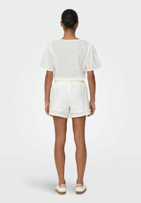 Ensemble en coton blanc composé de deux pièces, comprenant un haut à manches courtes ample orné de motifs floraux brodés et un short à taille élastique.