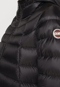 Černá prošívaná péřová bunda s prošívaným designem, vysokým límcem a zapínáním na zip, s kulatým logem značky na levé straně hrudi. Hladká textura.