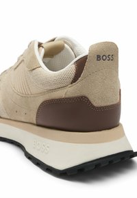 Sneaker beige in suede e mesh con un accento in pelle marrone, caratterizzato da un pannello posteriore testurizzato e una suola crema con battistrada nero.