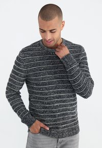 Gestrickter Pullover in Schwarz-Weiß-Streifen; runder Ausschnitt, lange Ärmel und gerippte Bündchen und Saum; strukturierten Stoff.