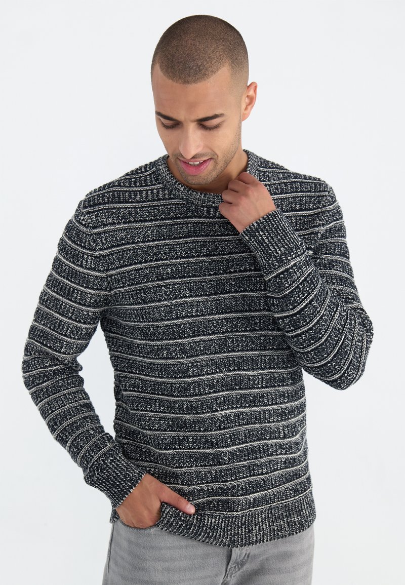 Gestrickter Pullover in Schwarz-Weiß-Streifen; runder Ausschnitt, lange Ärmel und gerippte Bündchen und Saum; strukturierten Stoff.