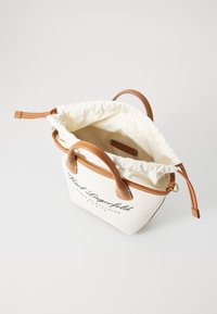 Leinen-Tote-Bag mit braunen Ledergriffen und -besatz, offener Kordelzugverschluss und schwarzem Logo-Text auf der Vorderseite.