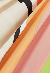 Tygerprover i olika färger: gräddvit med svarta ränder, orange, mjuk rosa och grön, som visar upp släta texturer och rena finishar.
