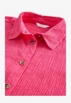 Crumpled pink shirt with a collar, featuring textured fabric and brown buttons down the front. Label reads "next."