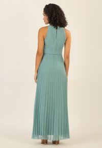 Ein ärmelloses, plissiertes Maxikleid in hellem Türkis mit hohem Kragen und subtilen Schlüssellochdetails im Rücken; glatte Textur, fließendes Design.