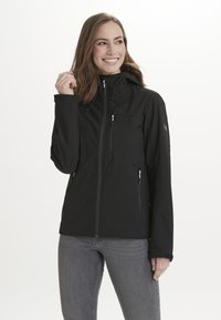 Svart zip-up jacka med två framlommor, justerbar huva och texturerad tygdetalj. Figursydd form, sömlös design och förstärkta ärmslut.