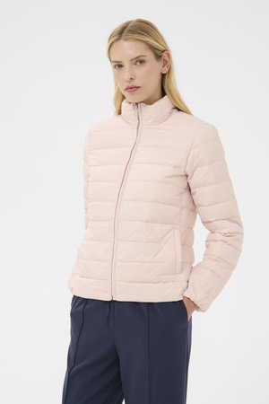 Light pink puffer jacket with a high collar, quilted design, front zipper, and side pockets, worn over navy trousers.