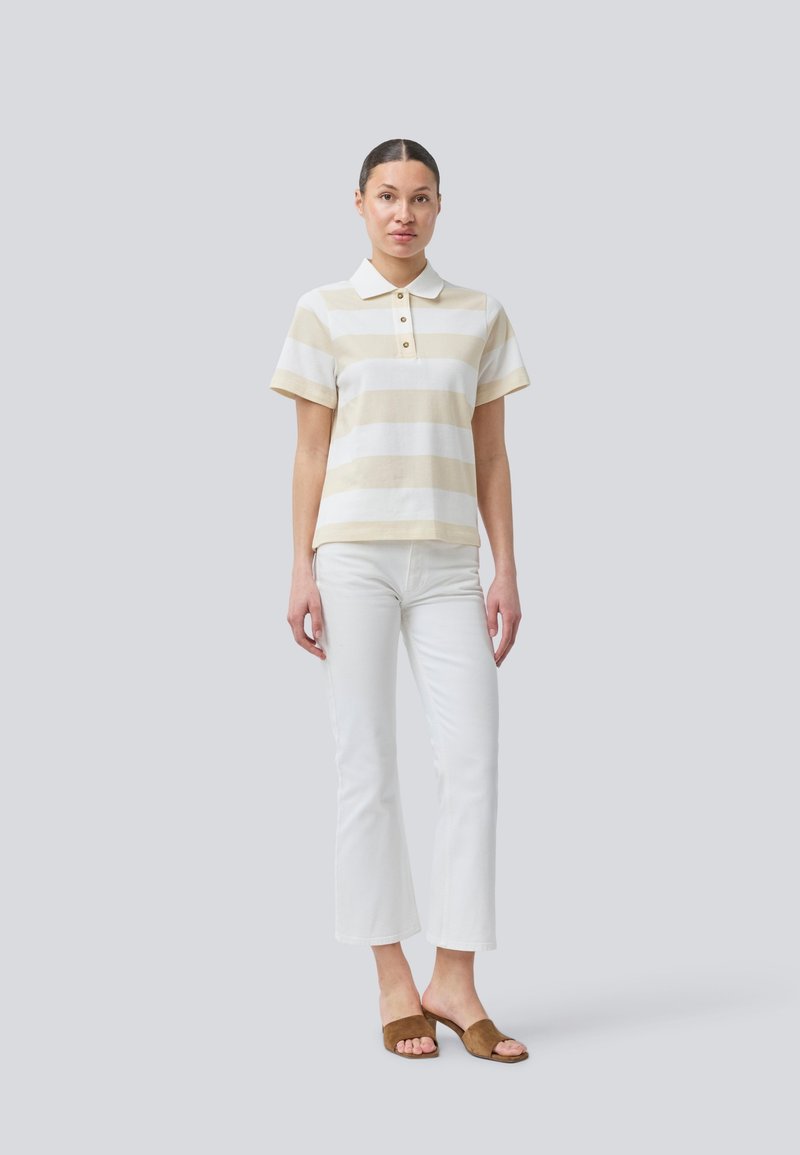 Polo shirt in crème en beige strepen, korte mouwen, met een drie-knopen placket; gecombineerd met witte flared broek en bruine slide sandalen.
