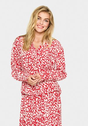 Rode en witte luipaardprint blouse met lange mouwen, knoopsluiting aan de voorkant en een relaxte pasvorm. Bevat een bijpassende rok met dezelfde print.