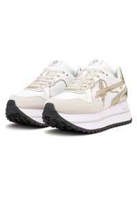 Vita och guld idrottsskor med överdel i mocka och mesh, texturerade snören, en tjock vit mellansula och en svart gummisula med greppmönster.