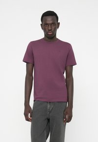 Tricou cu mânecă scurtă, guler rotund, de culoare burgundă închisă, realizat dintr-un material moale din bumbac, având un mic detaliu cu logo pe piept.