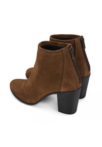 Bottes chelsea en daim marron avec un bout effilé, des fermetures éclair latérales et un talon en bloc noir. Texture lisse, design simple et sans motifs visibles.