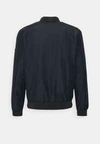 Veste bomber noire avec une surface lisse et brillante, col et poignets côtelés, taille élastique, sans éléments métalliques visibles ni détails de design.