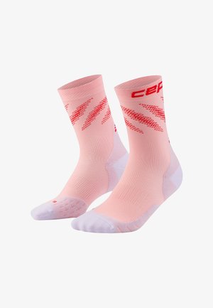 Pair of pink athletic socks with white heels and toes, red zigzag patterns on sides, and red brand name lettering near top cuff.