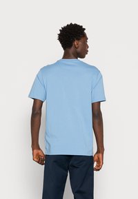 T-shirt de algodão azul claro com decote redondo, mangas curtas e um corte descontraído. Design simples sem padrões ou detalhes visíveis.
