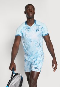 Hellblaues Sportshirt und Shorts mit Marmor-Muster, Kurzarm und V-Ausschnitt. Mit Logodetail auf der Brust.