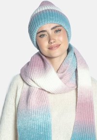Zestaw dzianinowej czapki i szalika w pastelowych kolorach gradientowych, z fakturą prążkowaną. Szalik elegancko opada, prezentując delikatny ombre w odcieniach różu i niebieskiego.
