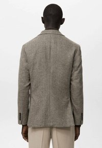 Hnědý blazer se vzorem pepito, strukturovaným střihem, klopy s výřezem a manžetami na knoflíky, zobrazený zezadu.