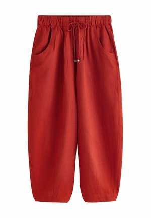 Väljävät punaiset housut joustavalla vyötärönauhalla ja kiristysnauhalla, joissa on sivutaskut ja leveä kapeneva lahje.