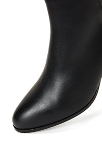Stivale alla caviglia in pelle nera con punta affilata e finitura liscia, caratterizzato da una silhouette elegante e un design minimalista.