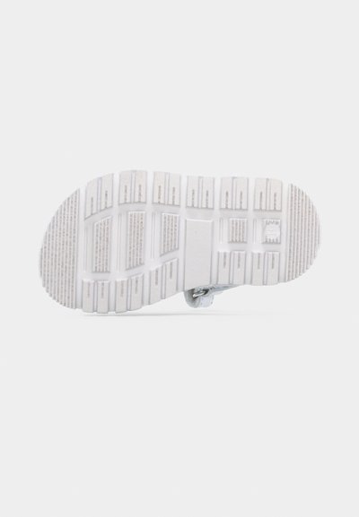 Λευκή σόλα παπουτσιού από καουτσούκ με βαθιά ορθογώνια και γραμμικά σχέδια πέλματος, απεικονιζόμενη από κάτω σε απλό φωτεινό φόντο.