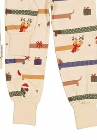 Cream-colored pants featuring a pattern of dachshunds, gift boxes, and holiday accents like reindeer antlers and Santa hats. Cuff detailing included.