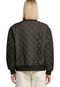 Schwarze gesteppte Bomberjacke mit rundem Kragen, elastischen Bündchen und Saum; glattes Material mit Rautensteppung.