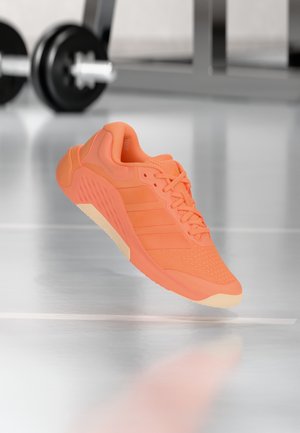 Oranger Sportschuh mit einem atmungsaktiven Mesh-Obermaterial, strukturierten Akzenten und drei seitlichen Streifen. Ausgestattet mit einer leichten Gummisohle.