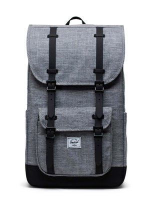 Zaino in tessuto grigio con dettagli neri, chiusura a patta, spallacci regolabili, tasca frontale e etichetta con logo distintivo nella parte inferiore.