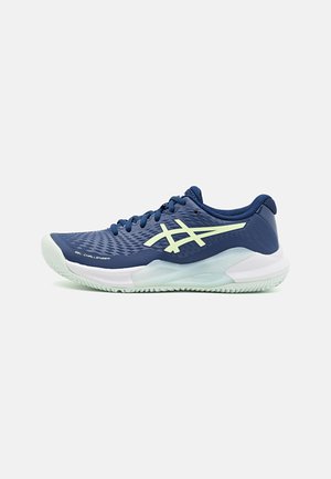 Blue athletic shoe with textured surface, white midsole, and green outsole. Features laces and a prominent logo design on the side.