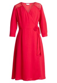 Robe rouge coupe droite avec des manches trois-quarts, des accents en dentelle sur les épaules et une ceinture à nouer à la taille. Tissu doux et silhouette fluide.