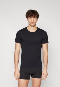 T-shirt noir à manches courtes en tissu doux et extensible, avec un design classique à col rond, une coupe ajustée et une texture unie.