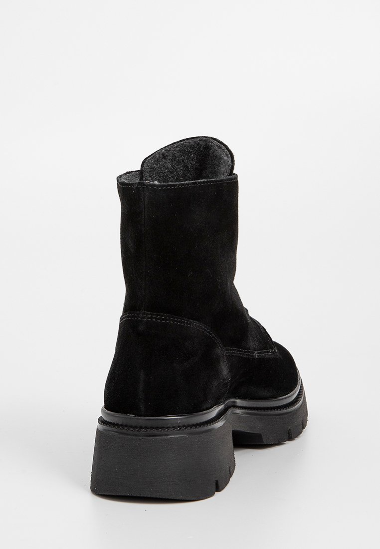Zwarte suède enkellaarzen met een ronde neus, een lage hak en een gladde zwarte rubberen zool. Naaddetails langs de achterkant bieden textuur.