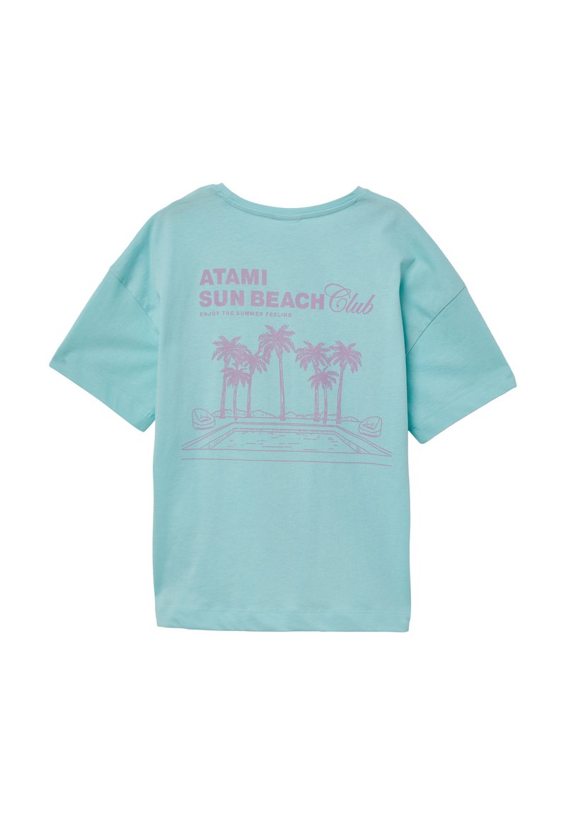 Lichtblauw katoenen t-shirt met een losse pasvorm. De voorkant heeft een roze grafisch ontwerp met palmbomen en de tekst "ATAMI SUN BEACH Club". Korte mouwen.