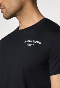 Zwarte korte mouwen t-shirt van katoen, met een witte geborduurde "BJÖRN BORG STOCKHOLM 1956" logo op de borst. Ronde halsontwerp.