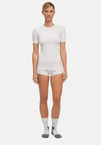 White short-sleeve top with ribbed texture, paired with matching shorts and gray-accented socks. Simple, form-fitting design.