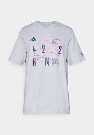 T-shirt en coton blanc avec un graphisme géométrique en rose et bleu marine, accompagné de texte et de chiffres. Manches courtes et encolure ras du cou.