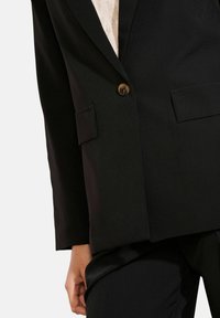 Črn blazer iz gladkega blaga, s klasičnim ovratnikom, enojnim zapiranjem na gumb in dvema sprednjima žepoma.