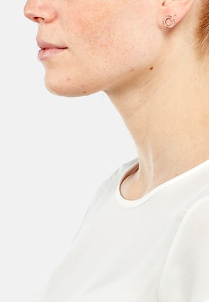 Orecchini a bottone in oro rosa con un design circolare, caratterizzati da un bordo testurizzato e un cerchio interno liscio. Indossati da una persona con pelle chiara.