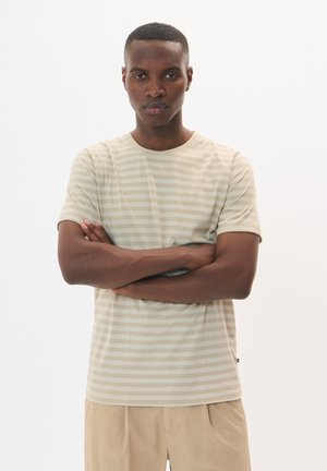 Light beige striped t-shirt made of cotton, featuring short sleeves and a crew neckline, paired with light textured shorts.