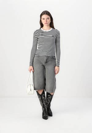 Striped black and white long-sleeve top, gray wide-leg jeans, black embroidered knee-high boots, white handbag with a zipper.