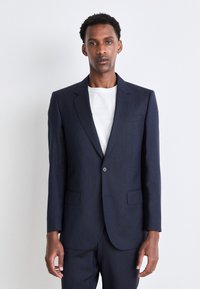 Blazer blu navy in un design su misura, caratterizzato da un bottone singolo, rever a punta e due tasche frontali. Tessuto liscio e strutturato.