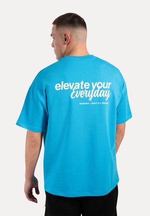 Blaues, oversized T-Shirt mit kurzen Ärmeln. Auf der Rückseite mit weißem Drucktext: "elevate your Everyday" und "Smilodox - Sport ist ein Lebensstil."