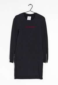 Svart långärmad klänning med rund halsringning och röd broderad text "son of a gun" på framsidan; har dragkedjedetaljer på ärmarna.