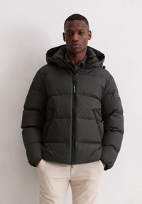 Czarna kurtka puchowa z kapturem, z przednim zamkiem błyskawicznym, poziomym pikowaniem oraz dwoma zamykanymi na zamek bocznymi kieszeniami. Nosi się ją na ciemną koszulę.