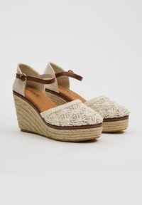 Sandalias de cuña en tejido beige con área del dedo bordada en crema, tira de tobillo marrón y detalles de suela de yute trenzado.