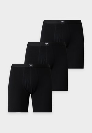 Tre sorte herre boxershorts med logo på linningen arrangeret i en forskudt linje på en lys baggrund.