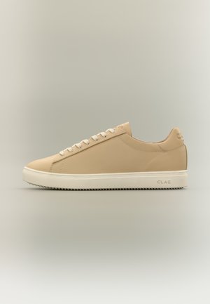 Beiger Leder-Sneaker mit niedrigem Schaft, weißen Schnürsenkeln und Sohle, strukturierter Grip sowie "CLAE"-Markierung an Ferse und Sohlenseite.
