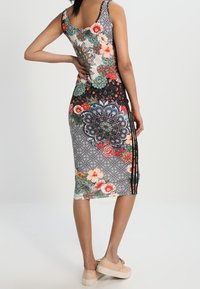Sukienka bez rękawów, dopasowana, z kwiatowymi i geometrycznymi wzorami w żywych kolorach. Czarne boczne panele z paskami. Miękka tkanina, długość do kolan.